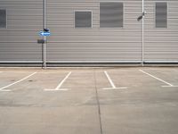 the corner of a parking lot in front of a building with shuttered window openings