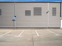 the corner of a parking lot in front of a building with shuttered window openings