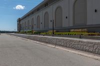 a small road runs along side a large building with columns and arches on the wall