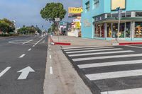 a blue building and a yellow store are on the corner of the street with two white arrow arrows