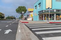 a blue building and a yellow store are on the corner of the street with two white arrow arrows