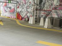 a painted wall in a parking garage next to yellow cones and a blue pole, which are holding a green traffic light