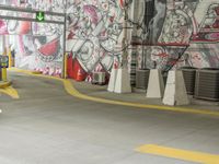 a painted wall in a parking garage next to yellow cones and a blue pole, which are holding a green traffic light