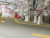 a painted wall in a parking garage next to yellow cones and a blue pole, which are holding a green traffic light