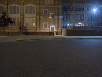 a street light on a dark and empty street by a high school building in the city