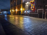 a street in the middle of an old brick street at night with neon lighting from several lights