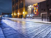 a street in the middle of an old brick street at night with neon lighting from several lights