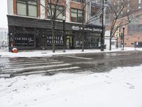 snow covers the streets near a large city building in winter time and pedestrian crossing signs