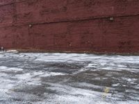 there is an empty parking lot next to a brick building with snow on the ground