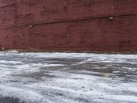 there is an empty parking lot next to a brick building with snow on the ground