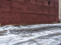 there is an empty parking lot next to a brick building with snow on the ground