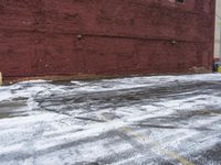 there is an empty parking lot next to a brick building with snow on the ground