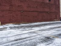there is an empty parking lot next to a brick building with snow on the ground