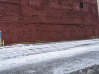 there is an empty parking lot next to a brick building with snow on the ground