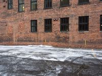 a street is covered in snow on an urban building street curb with building windows and red fire hydrant