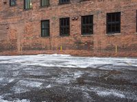 a street is covered in snow on an urban building street curb with building windows and red fire hydrant