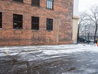 a street is covered in snow on an urban building street curb with building windows and red fire hydrant