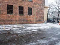 a street is covered in snow on an urban building street curb with building windows and red fire hydrant