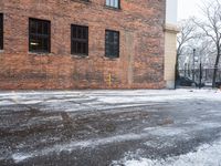 a street is covered in snow on an urban building street curb with building windows and red fire hydrant