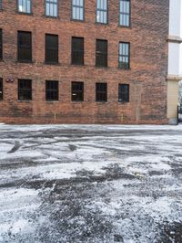 a street is covered in snow on an urban building street curb with building windows and red fire hydrant