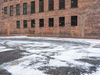 a street is covered in snow on an urban building street curb with building windows and red fire hydrant