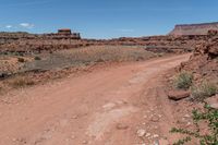 dirt road leading through an arid and rocky desert plain to a cliff in the distance