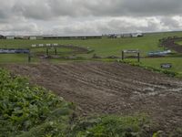 two dirt motocross racers riding a muddy track through a grassy field on cloudy day