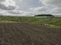 two dirt motocross racers riding a muddy track through a grassy field on cloudy day