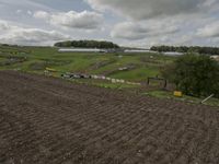 two dirt motocross racers riding a muddy track through a grassy field on cloudy day