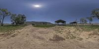 an image of two horses under a shade hut at the end of a dirt path