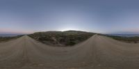 a guy rides his skateboard down a dirt path at sunrise by the beach on a bike