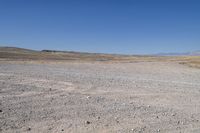 a stop sign is in the middle of a barren field surrounded by mountains and arid areas