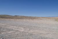 a stop sign is in the middle of a barren field surrounded by mountains and arid areas