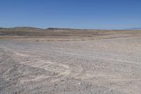 a stop sign is in the middle of a barren field surrounded by mountains and arid areas