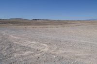 a stop sign is in the middle of a barren field surrounded by mountains and arid areas