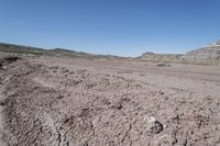 dirt road at badlands area with rocky formation and blue sky in background under bright blue skies