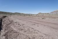 dirt road at badlands area with rocky formation and blue sky in background under bright blue skies