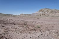 dirt road at badlands area with rocky formation and blue sky in background under bright blue skies