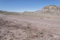 dirt road at badlands area with rocky formation and blue sky in background under bright blue skies