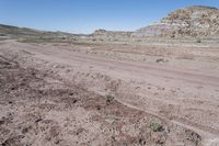 dirt road at badlands area with rocky formation and blue sky in background under bright blue skies