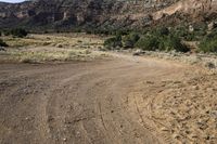 an open dirt road leads through a barren landscape and into a mountainous valley, with a truck on it