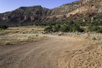 an open dirt road leads through a barren landscape and into a mountainous valley, with a truck on it