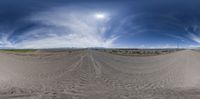 a panorama lens view of a dirt road running through an open field in the distance