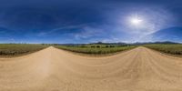 this is a fisheye lens reflection on a dirt road in the countryside near an agricultural land