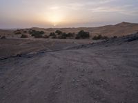 a truck on a dirt road in the desert with rocks and stones on the ground