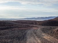 a dirt road running through an outcropping, in the middle of the desert