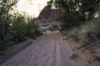 a dirt road runs through the middle of a desert landscape with an old rock wall