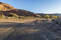 a view from the side of the dirt road looking towards a cabin in a canyon