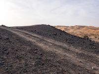 a truck on a dirt road in the desert with rocks and stones on the ground