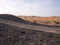 a truck on a dirt road in the desert with rocks and stones on the ground